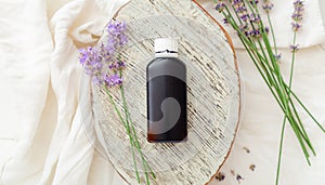 Lavender essential oil bottle on white wooden rustic board with fresh lavender flowers. Aromatherapy treatment, natural spa
