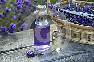 Lavender Essential oil bottle on wood table and flowers field background