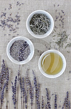 Lavender essential oil, dry herb in a bowl with flowers nearby