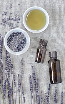 Lavender essential oil, dry herb in a bowl with flowers nearby