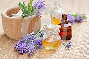 Lavender essential oil and extract in glass bottle with fresh flower and leaf on rustic wooden background