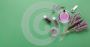 Lavender essential oil glass bottle serum dropper on green color background. Fresh lavender flowers. Aromatherapy treatment.