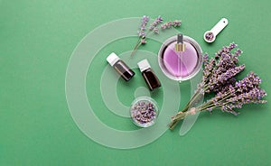 Lavender essential oil glass bottle serum dropper on green color background. Fresh lavender flowers. Aromatherapy treatment,