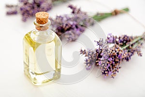 Lavender essential oil glass bottle on white wooden rustic table fresh lavender flowers. Aromatherapy treatment, natural spa