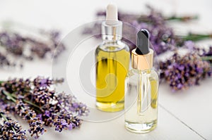Lavender essential oil glass bottles, serum, dropper on white wooden rustic table fresh lavender flowers. Aromatherapy treatment,