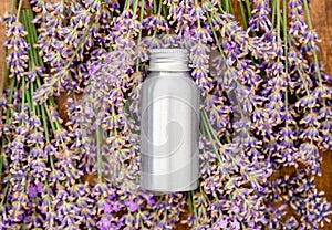 Lavender essential oil metal silver bottle on fresh lavender flowers. Flat lay apothecary herbs for aromatherapy treatment.