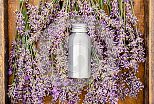 Lavender essential oil metal silver bottle on fresh lavender flowers in wooden box. Flat lay apothecary herbs for aromatherapy