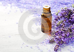 Lavender essential oil, sprigs of lavender and mineral bath salts on the wooden table. Selective focus photo