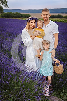 In a lavender field, mom, dad, and two little daughters are enjoying a happy family moment