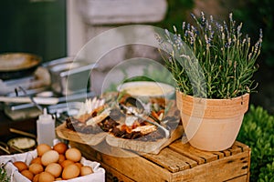 Lavender in a flower pot on a wooden box with cutting boards with cold cuts and chicken eggs in a box.