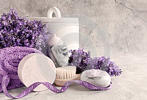 Lavender flowers, candle in the marble candlestick, aroma bath salt, other hygiene supplies and towels on marble background