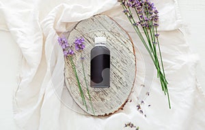 Lavender flowers with lavender essential oil bottle on white wooden rustic board and fabric. Aromatherapy treatment, natural