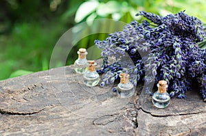 Lavender flowers and lavender oil on a wooden table. Natural lavender oil in transparent bottles with selective focus