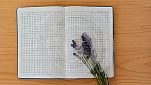 Lavender flowers on the page of an open notebook on the background of the table