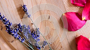 Lavender flowers with red rose petals on wood background