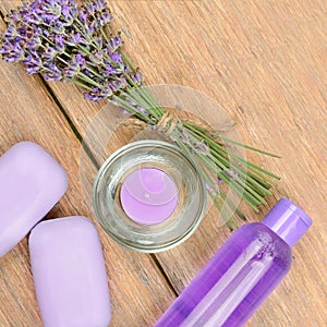 Lavender flowers, soap, scented candle and shampoo on a wooden background