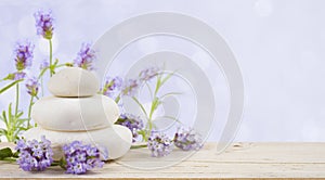 Lavender flowers and stones on wood over abstract lilac background