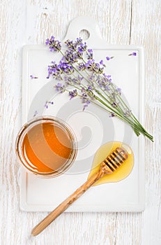Lavender honey in glass jar with flowers on white background