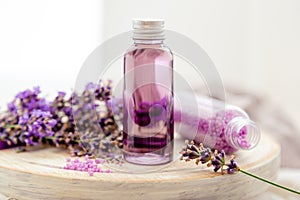 Lavender liquid. Bath cosmetics products in bottles on white wooden rustic board, fresh lavender flowers, soap, bath beads.