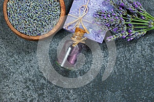 Lavender natural soap and lavender oil with fresh lavender flowers and dried lavender seeds on grey rustic table