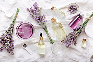 Lavender oils serum and lavender flowers on white fabric. Skincare cosmetics products. Set natural spa beauty products. Lavender