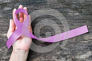 Lavender purple cancer all kinds awareness ribbon on people`s hand support with aged wood background