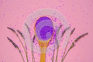 lavender salt.Cosmetic lilac salt in wooden spoon and lavender flowers on a pink background.purple bath salt.Flower bath