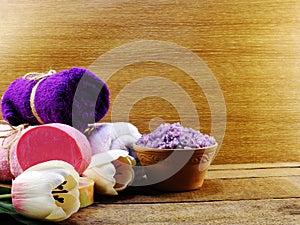 Lavender salt spa and roll of towel on wooden background