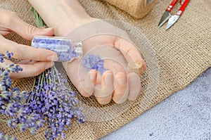 Lavender salt for spa treatments. Lavender sea salt in a small transparent bottle in female hands and fresh lavender