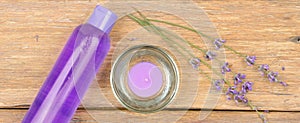 Lavender shampoo, scented candle, dried lavender flowers on a wooden background