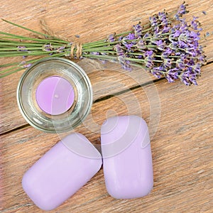 Lavender soap, scented candle, dried lavender flowers on a wooden background