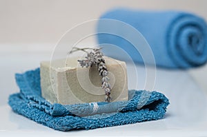 Lavender soap on washcloth and rolled blue towel in t