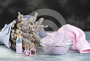 Lavender spa setting: salt, essential oil and dried flowers natural spa products and decor for bath on light background