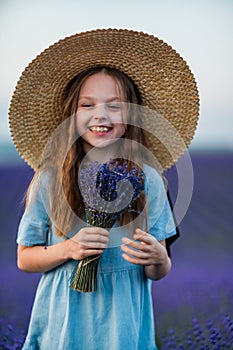 Lavender sunset girl. A laughing girl in a blue dress with flowing hair in a hat walks through a lilac field, holds a