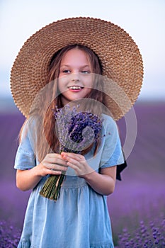 Lavender sunset girl. A laughing girl in a blue dress with flowing hair in a hat walks through a lilac field, holds a