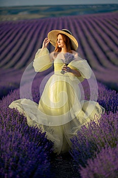 Lavender sunset girl. A laughing girl in a blue dress with flowing hair in a hat walks through a lilac field, holds a