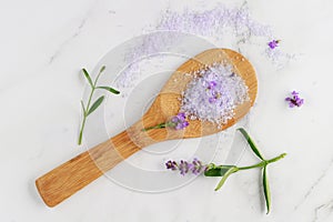 Lavender violet salt on wooden spoon and fresh flowers on white marble background