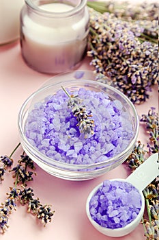 Lavender violet sea salt with lavender flowers, candle. Lavender bath products Aromatherapy treatment on pink color background.