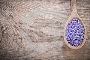 Lavender violet sea salt in wooden spoon on wood board spa treat