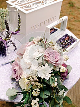 Lavender wedding. Wedding rings with purple floral decorations on white table