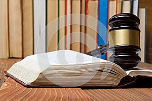 Law book with wooden judges gavel on table in a courtroom or law enforcement office.