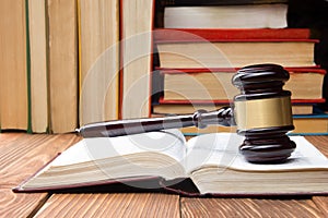 Law book with wooden judges gavel on table in a courtroom or law enforcement office.