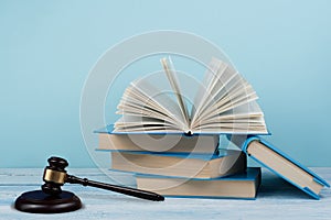 Law concept open book with wooden judges gavel on table in a courtroom or law enforcement office, blue background. Copy