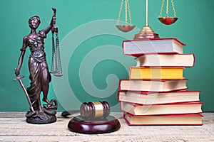 Law concept - Open law book, Judge's gavel, scales, Themis statue on table in a courtroom or law enforcement office