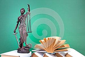 Law concept - Open law book, scales, Themis statue on table in a courtroom or law enforcement office