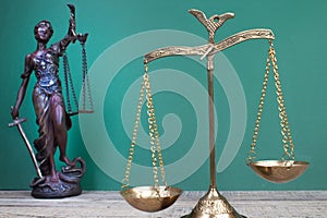 Law concept - Open law book, scales, Themis statue on table in a courtroom or law enforcement office