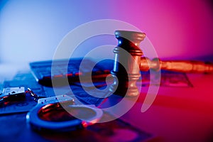 Law gavel with dollars and handcuffs on a table close-up