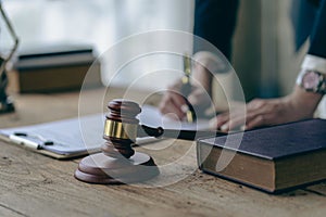 Law and Justice Lawyer working with documents and laptop, hammer, scale at wooden table in office Close-up