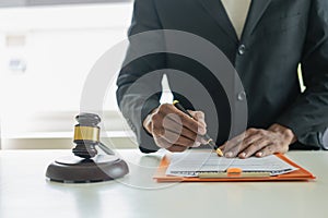 Law and Justice Lawyer working with documents and laptop, hammer, scale at wooden table in office Close-up