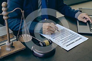 Law and Justice Lawyer working with documents and laptop, hammer, scale at wooden table in office Close-up